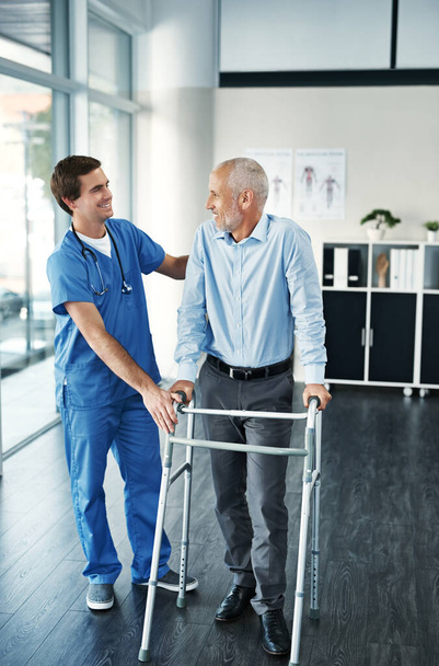 Youre made some great improvement. Shot of a male nurse assisting a senior patient with a walker. - Photo, Image