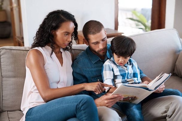 Estamos a ler o seu livro favorito outra vez. Tiro de um homem jogando videogames enquanto relaxa em casa com sua esposa e filho. - Foto, Imagem