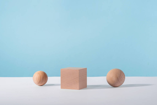 Wooden cube podium with sphere on blue background for cosmetic or jewellery showcase. Creative geometric product stage mock up, cosmetics display platform, product advertising - Foto, immagini