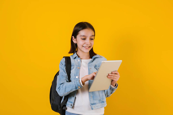 Niña latina estudiante sosteniendo una tableta digital sobre fondo amarillo en México América Latina - Foto, imagen