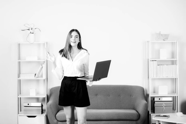 Young businesslady with laptop and credit card at workplace in the office. Secretary woman in formal wear working on project at modern office. - 写真・画像