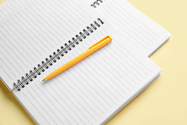 Cuadernos y pluma sobre fondo amarillo claro - Foto, Imagen