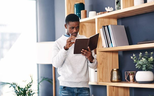 Establece metas y hazlas realidad. Fotografía de un joven empresario leyendo un cuaderno en una oficina moderna. - Foto, imagen