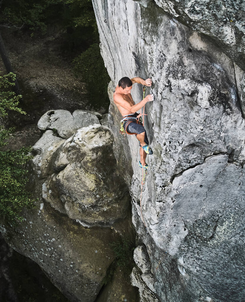 Αρσενικός ορειβάτης εκπαιδεύει αναρρίχηση σε ένα τεράστιο βράχο - Φωτογραφία, εικόνα