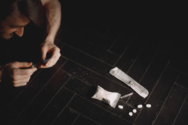 A drogos férfi a fecskendőért nyúl az adagjával - Fotó, kép