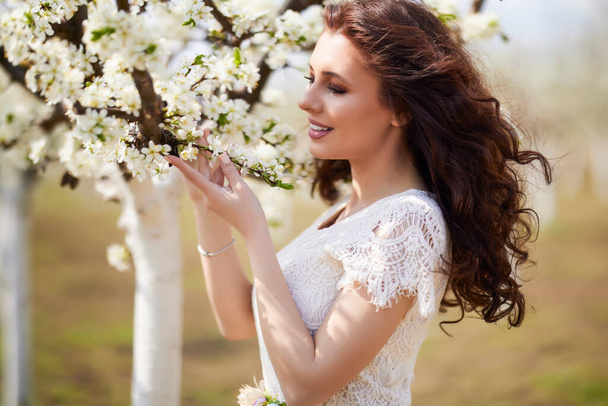 Портрет красивої жінки з довгим волоссям біля квітучих дерев навесні
. - Фото, зображення
