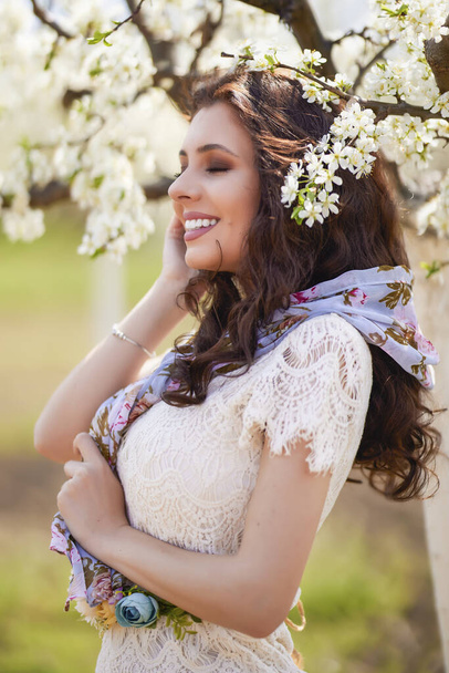 Portrait of a beautiful woman with long hair near flowering trees in spring. - Foto, Imagem