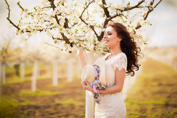 Ritratto di una bella donna con i capelli lunghi vicino agli alberi in fiore in primavera. - Foto, immagini