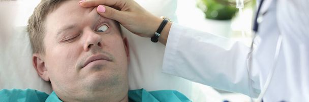 Tohtori avaa silmänsä potilaan tajuttomalle klinikalle - Valokuva, kuva