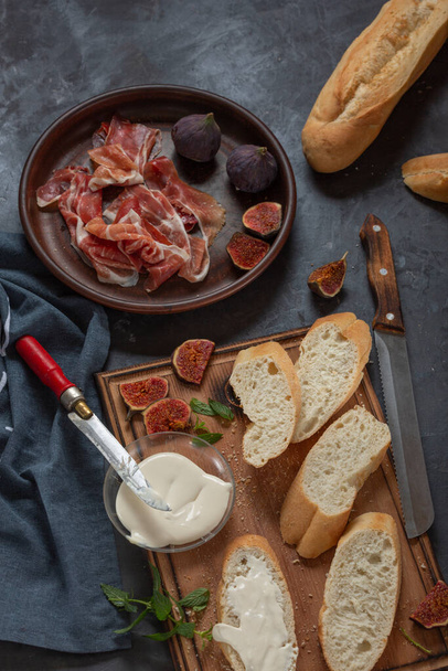 Jamon with figs and a baguette with cream cheese on the dining table, appetizer for wine, Spanish cooking. - Fotografie, Obrázek