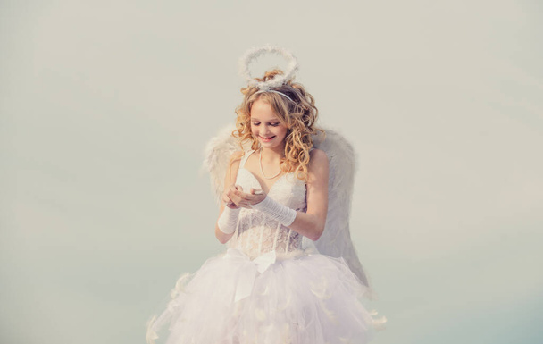 Angel child girl with curly blonde hair. Festive Art Greeting Card. Arrow of love. Charming curly little girl in white dress and wings - angel cupid girl. - Foto, Imagen