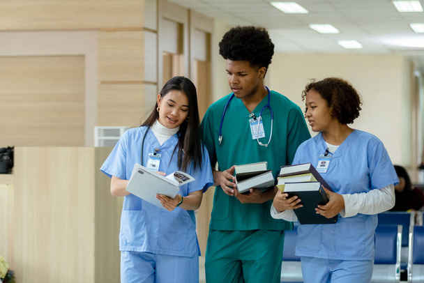 grupa studentów medycyny trzymających książki spaceru i rozmowy na uniwersytecie. edukacja i uczenie się koncepcji medycznej. - Zdjęcie, obraz