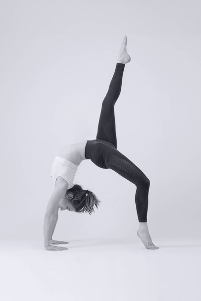 Schwarz-Weiß-Fotoserie von jungen, fitten Frauen, die Yoga praktizieren. Studioaufnahme auf weißem Hintergrund. - Foto, Bild