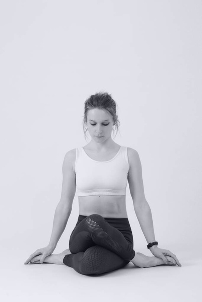 Yoga yapan genç fit bir kadının siyah beyaz fotoğrafları. Beyaz arkaplanda stüdyo görüntüsü. - Fotoğraf, Görsel