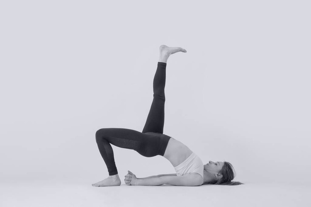 Musta ja valkoinen sarja kuvia joogaa harjoittavasta nuoresta naisesta. Studio ammuttiin valkoisella taustalla. - Valokuva, kuva
