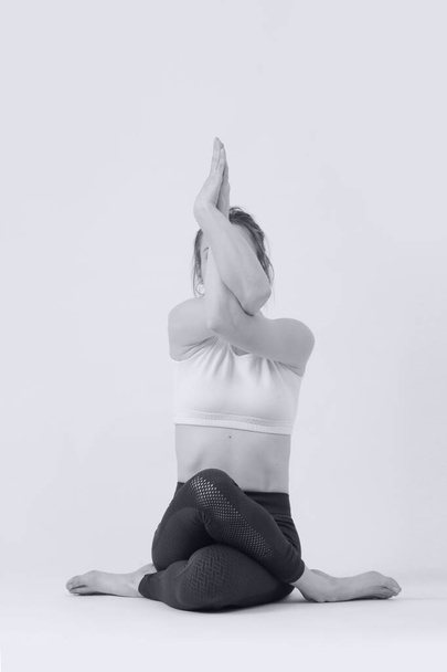 Zwart-wit serie foto 's van jonge fitte vrouw die yoga beoefent. Studio shot op witte achtergrond. - Foto, afbeelding