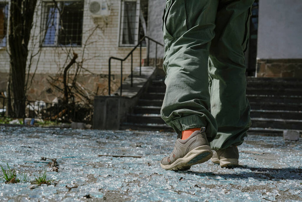  A man in green pants walks on broken glass. Pieces of broken glass lie on the sidewalk after the explosion. - 写真・画像
