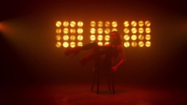 Meisje met erotische bewegingen zittend op een clubstoel. Hot danser verhogen benen. - Video