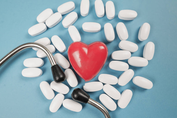 Weiße medizinische Tabletten rotes Herz und Stethoskop. Nahaufnahme. Medizinisches Konzept. - Foto, Bild