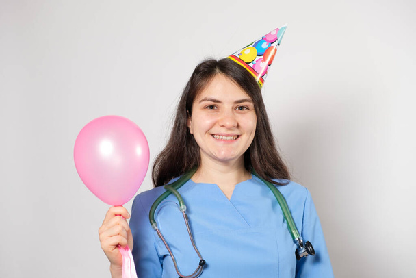 De dokter houdt een feestelijke ballon en glimlacht, gelukkige doktersdag - Foto, afbeelding
