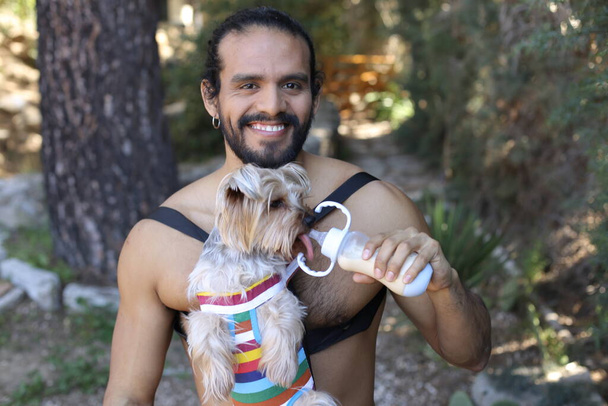 close-up portret van knappe shirtloze jonge man dragen schattig hondje - Foto, afbeelding