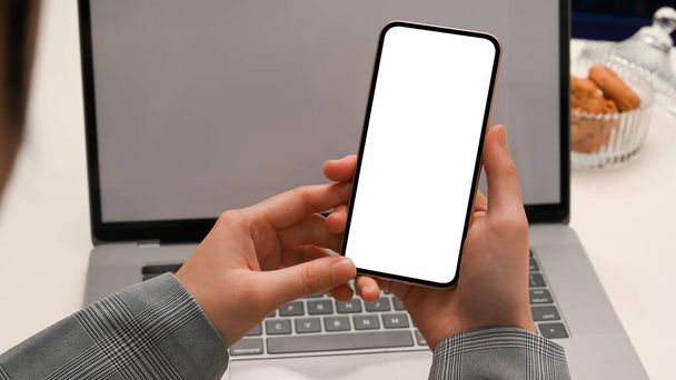 Modern ofis işyerinin üzerinde akıllı telefon beyaz ekran modeli tutan kadın eller. yakın plan - Fotoğraf, Görsel