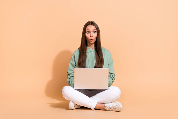 Portrait of beautiful trendy amazed girl sitting using laptop pout lips isolated over beige pastel color background - Photo, Image