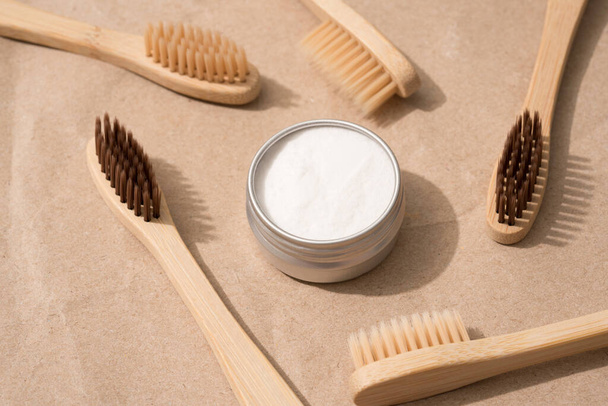 Natural wooden bamboo toothbrushes with natural bristle and mineral toothpowder on kraft paper background. Natural bath products, organic dentifrice. Mockup image, top view - Photo, image