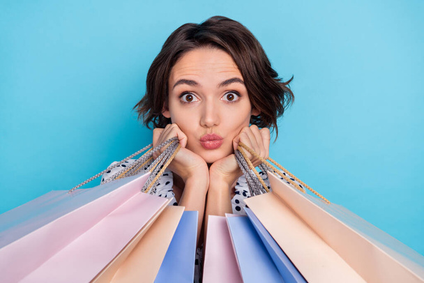 Portrait of pretty positive girl hold packages pouted lips look camera isolated on blue color background - Foto, Bild
