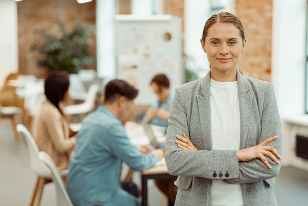 Smiling woman standing in a coworking space and clasped her hands - Фото, изображение
