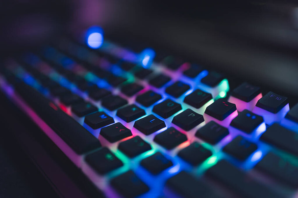 Bunt beleuchtete Gamer-Tastatur mit schwarzen Druckknöpfen. Rot, grün, blau, rosa. - Foto, Bild