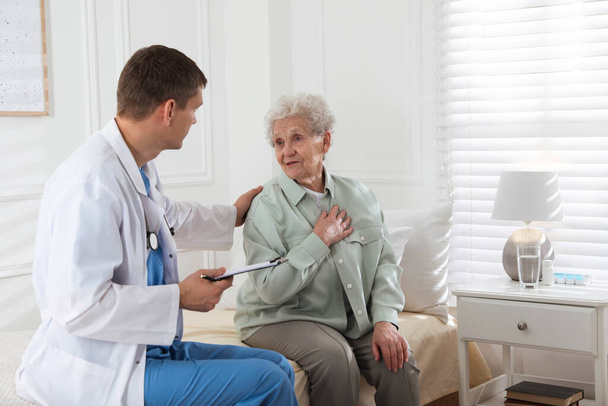 Caregiver examining senior woman in room. Home health care service - Фото, зображення
