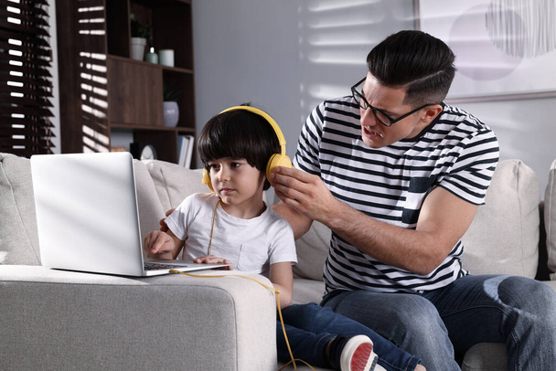 Internet addiction. Man scolding his son while he using laptop in living room - Foto, Bild