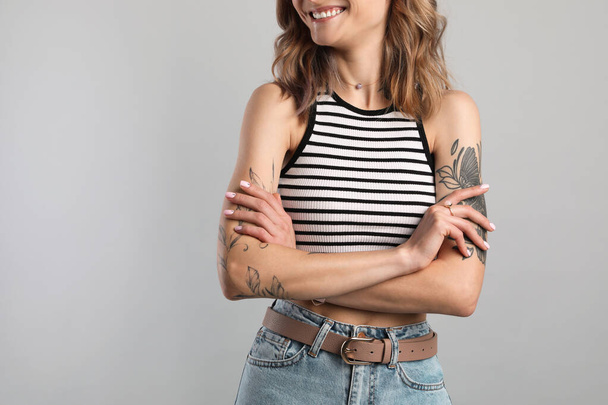 Beautiful woman with tattoos on body against grey background, closeup - 写真・画像