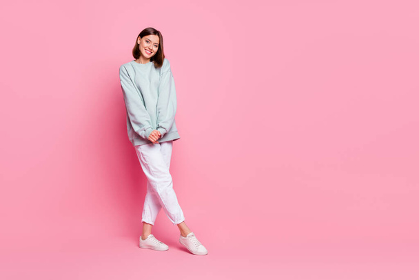 Full length photo of pretty milennial lady stand wear hoodie pants footwear isolated on pink background - Foto, afbeelding