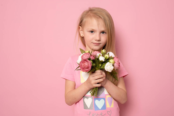 Fénykép vidám édes aranyos kis kaukázusi hölgy kezét tartsa jelen csokor friss természetes virágok mosoly elszigetelt rózsaszín szín háttér - Fotó, kép