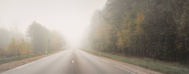 Empty asphalt road (highway) in a thick fog. Concept urban autumn landscape. Transportation, dangerous driving, speed, freedom, travel, tourism, vacations, emptiness, loneliness, the way forward - Fotó, kép