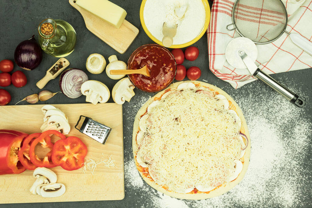 Składniki na stole do robienia pizzy. Proces gotowania pizzy: ciasto, wałek, jajka, masło i mąka pszenna na drewnianym stole. Tło z miejscem na tekst - Zdjęcie, obraz