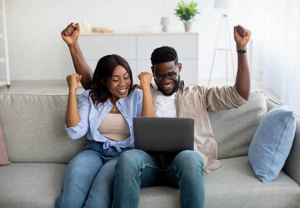African american couple sitting on couch, using pc - 写真・画像
