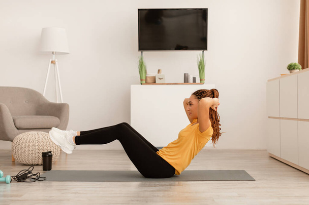 Vista lateral da mulher se exercitando fazendo abdominais rachaduras em casa - Foto, Imagem