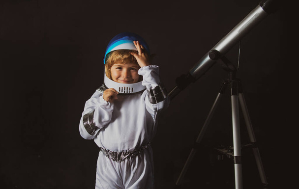 Child boy with a telescope imagines himself to be an astronaut in an space helmet. Astronomy and astrology concept. - Foto, Imagem
