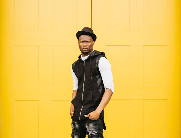 Portrét mladého černocha stojícího proti žlutým dveřím - Fotografie, Obrázek