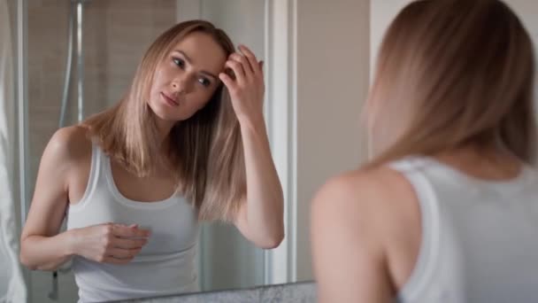 Běloška kontroluje stav vlasů v koupelně. Snímek s RED heliovou kamerou v 8K.  - Záběry, video