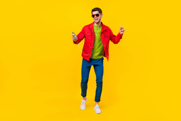 Full body photo of funky young guy dance listen music wear glasses shirt pants sneakers isolated on yellow background - Foto, immagini