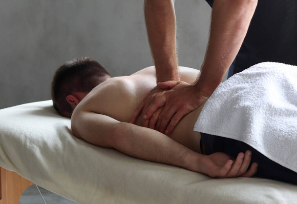 Therapist doing back sports massage to male patient athlete at studio - 写真・画像