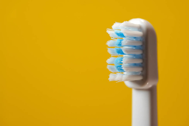 Electric ultrasonic toothbrush bristles on yellow background. - Foto, afbeelding