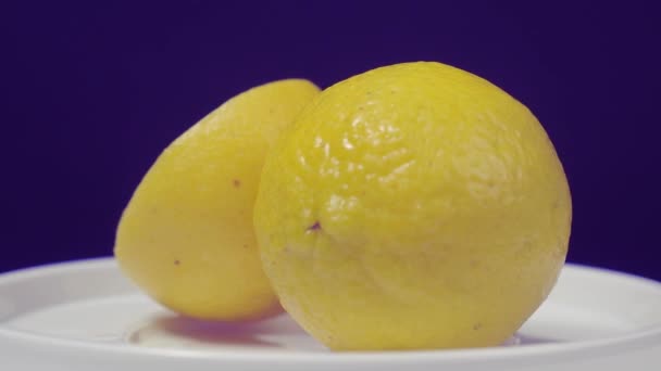 Lahodný citron na točitém stole. Chutné citrony izolovat na černém pozadí. Celé a napůl žluté citrony jsou izolovány na tmavém pozadí. Zblízka. Reprezentovat kyselé a osvěžující nápojové menu. - Záběry, video