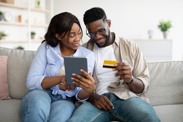 casal preto usando tablet e cartão de débito em casa - Foto, Imagem