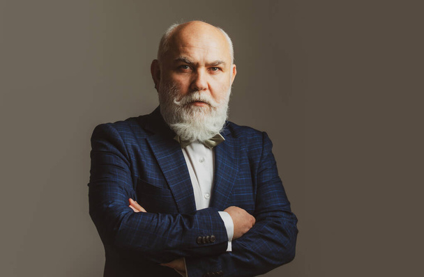 Confident businessman posing with folded arms Senior Man. Head and shoulders portrait of a bearded middle-aged man over a gray studio background with copy space. - Foto, imagen