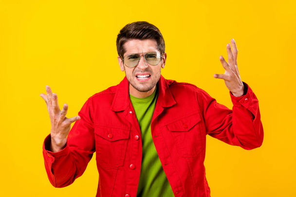 Photo of angry millennial brunet guy yell wear red shirt eyewear isolated on yellow color background - Foto, Imagem